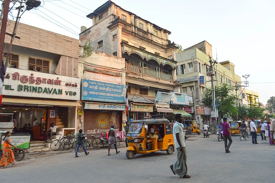 A busy street in Madurai lined with multi-storey buildings and shops, Tamil Nadu