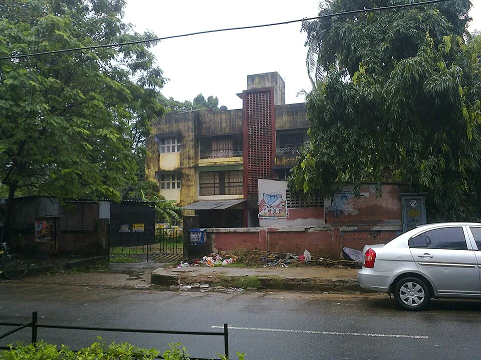 Residential street with an apartment building behind trees in Tamil Nadu
