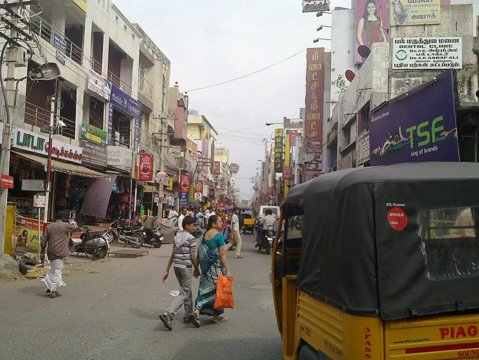 Bazaar street in Salem lined with shops, signboards and parked autos
